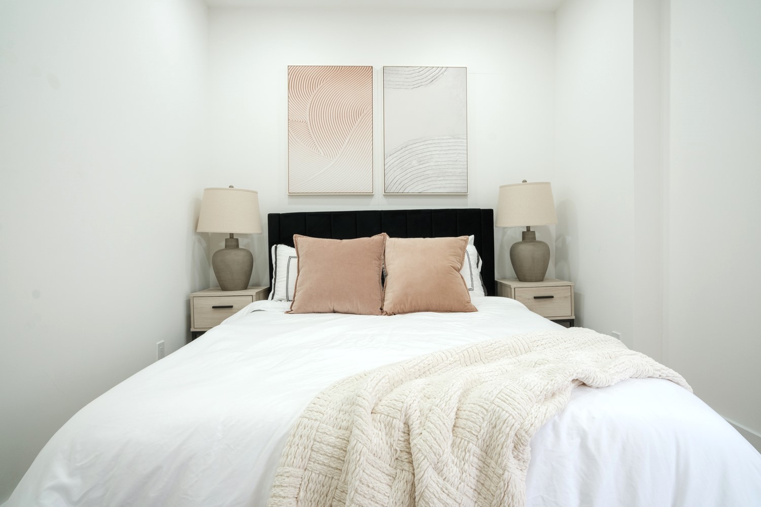 Bedroom with black velvet headboard, blush velvet pillows and textured art