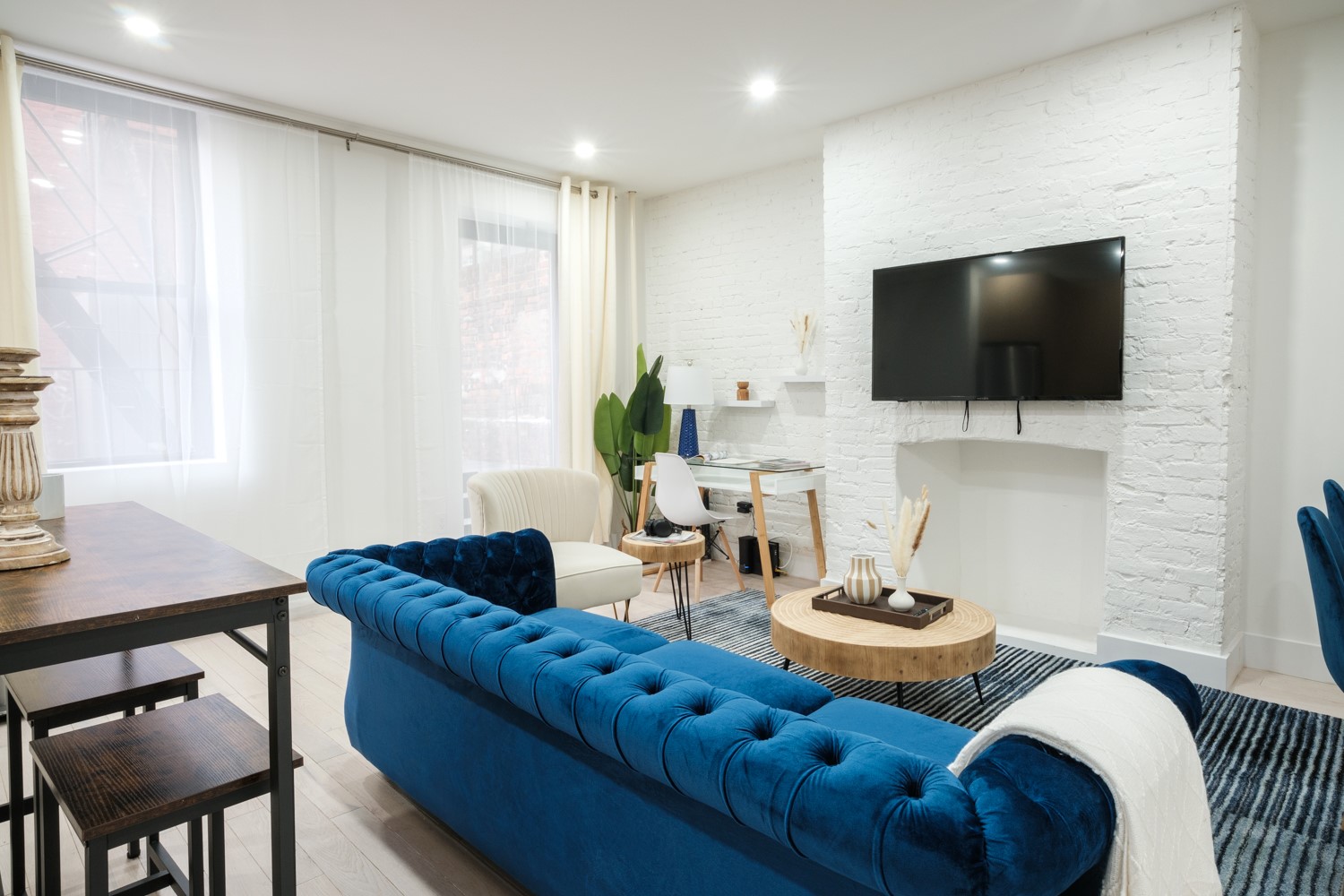 Living room with a velvet sofa, exposed brick and big windows